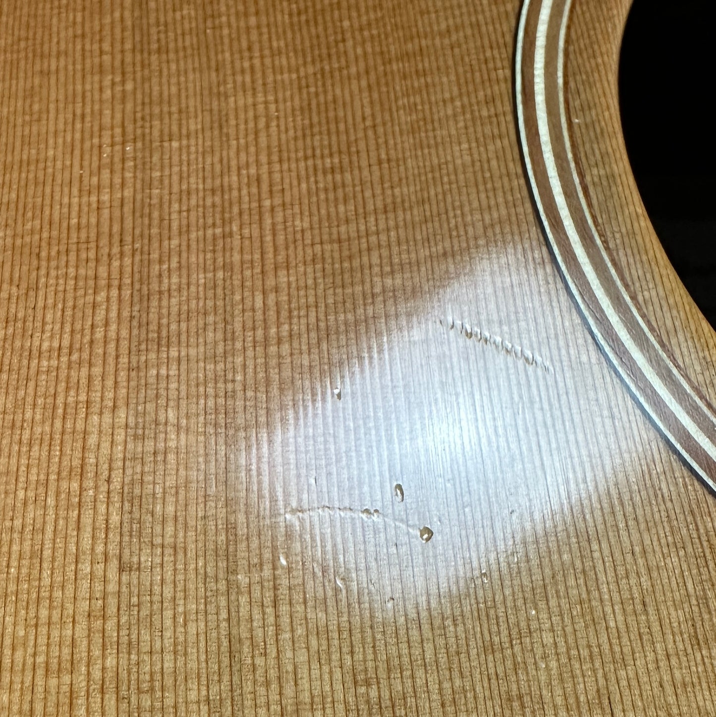 Damage near soundhole of Used Lowden O-25.