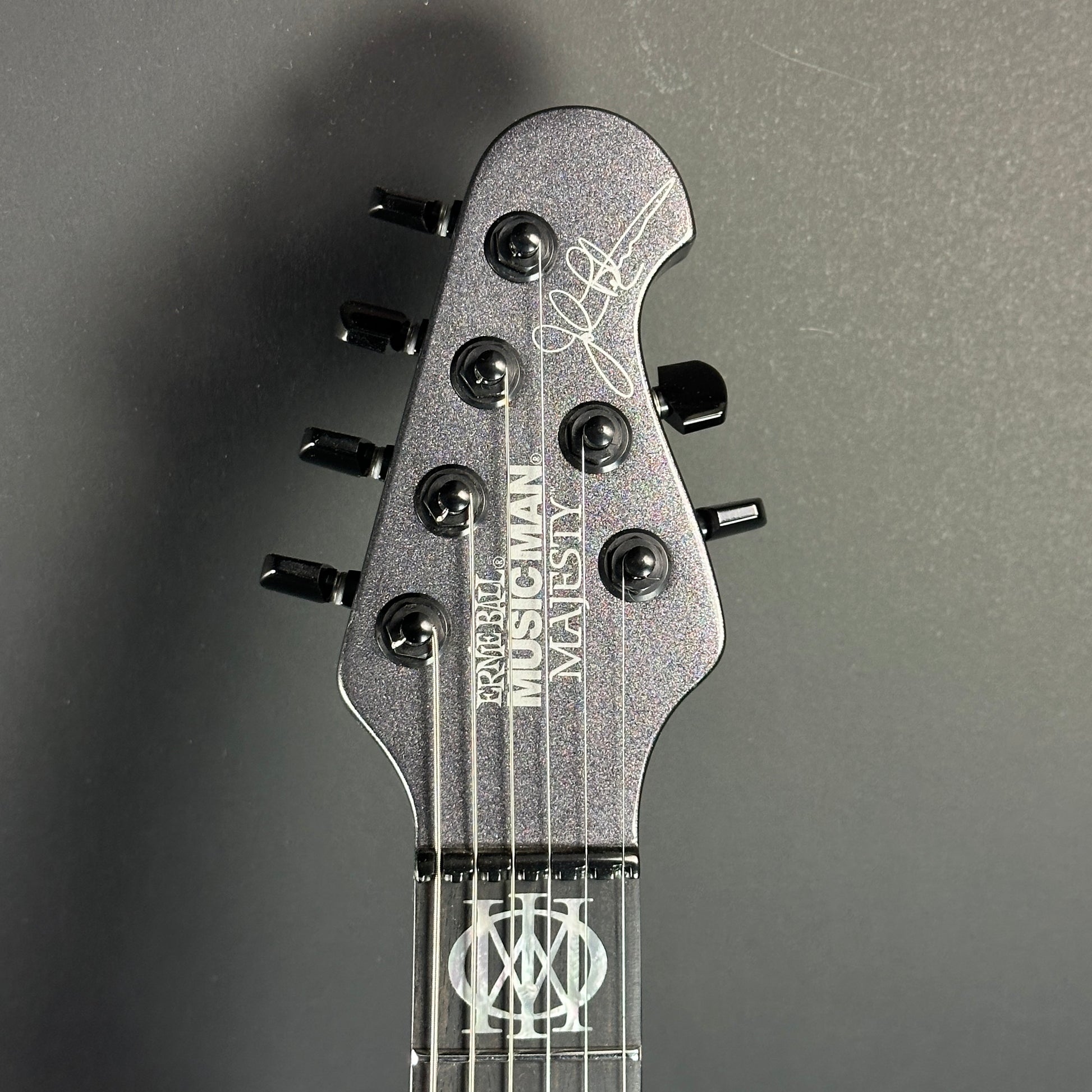 Front of headstock of Used Ernie Ball Musicman Majesty 6 John Petrucci Smoked Pearl.