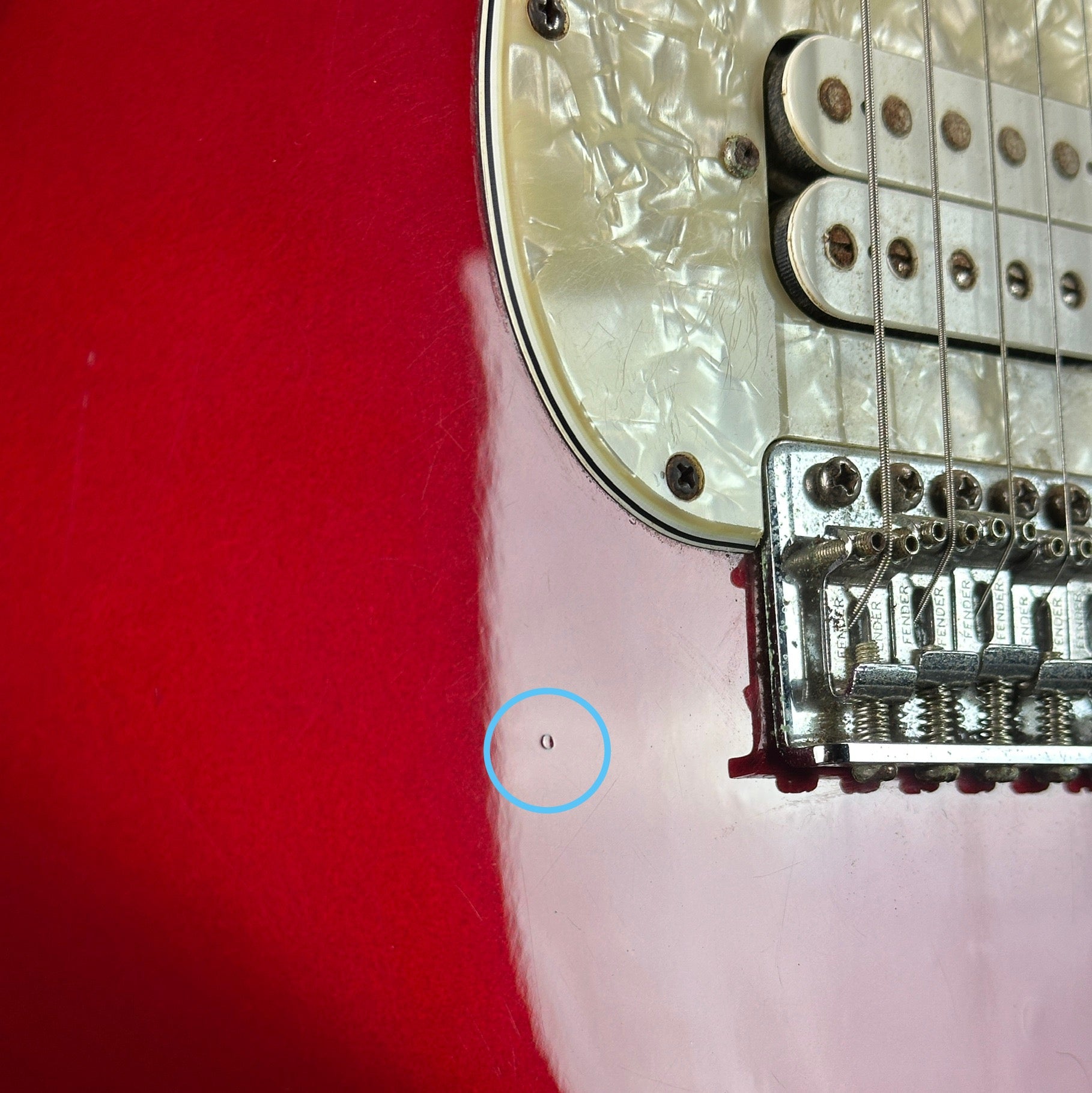 Ding near bridge of Used 2006 Fender Sam Ash 48th Street Red Strat.