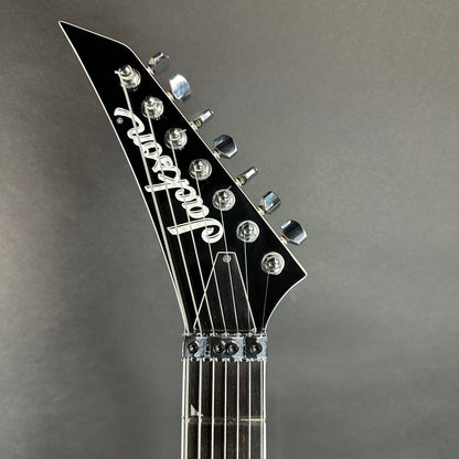 Front of headstock of Used Jackson Pro Series SL7 Ebony Fretboard Gloss Black.