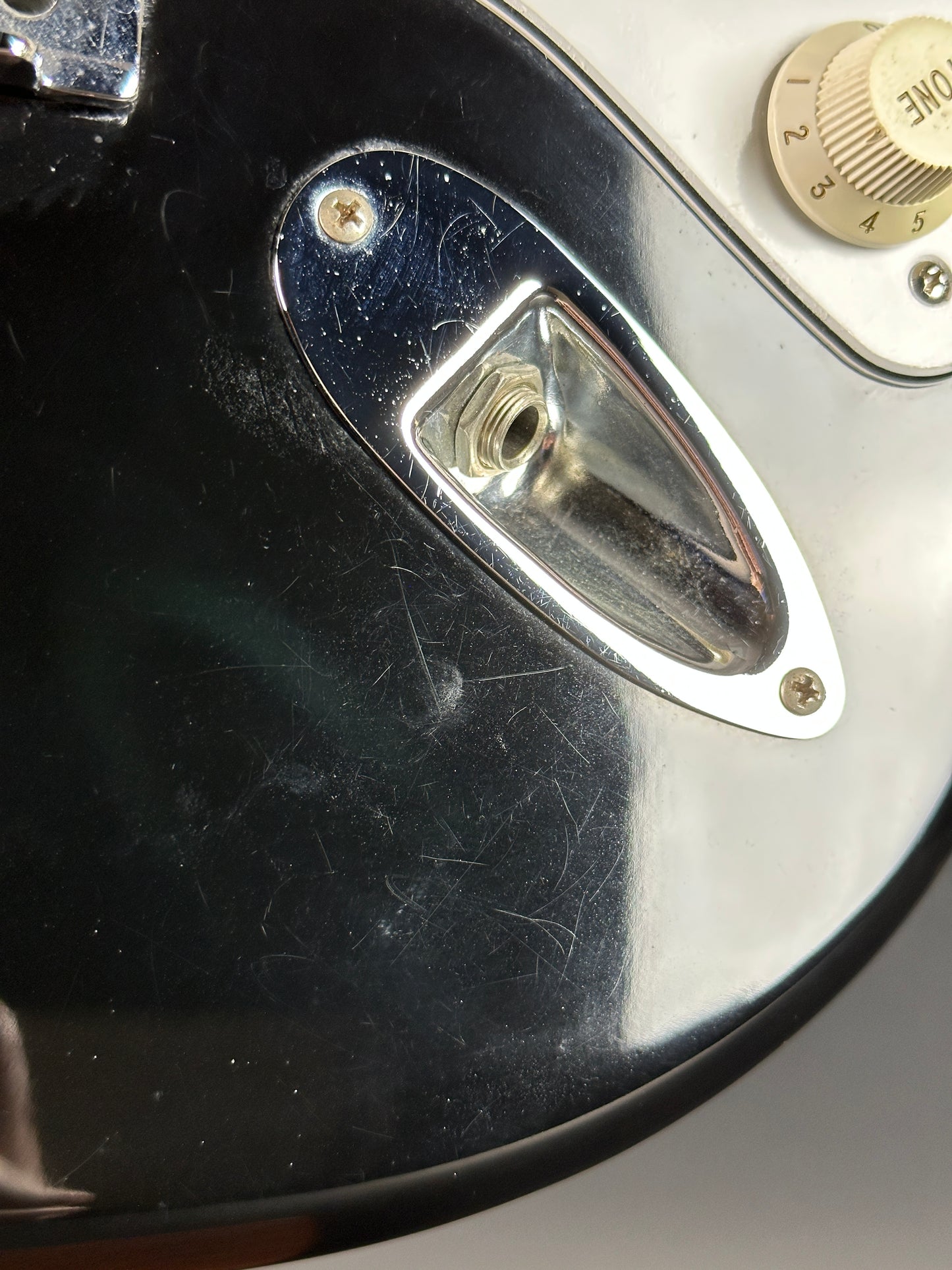 Scratches near output jack of Used Fender MIM Standard Strat Black.