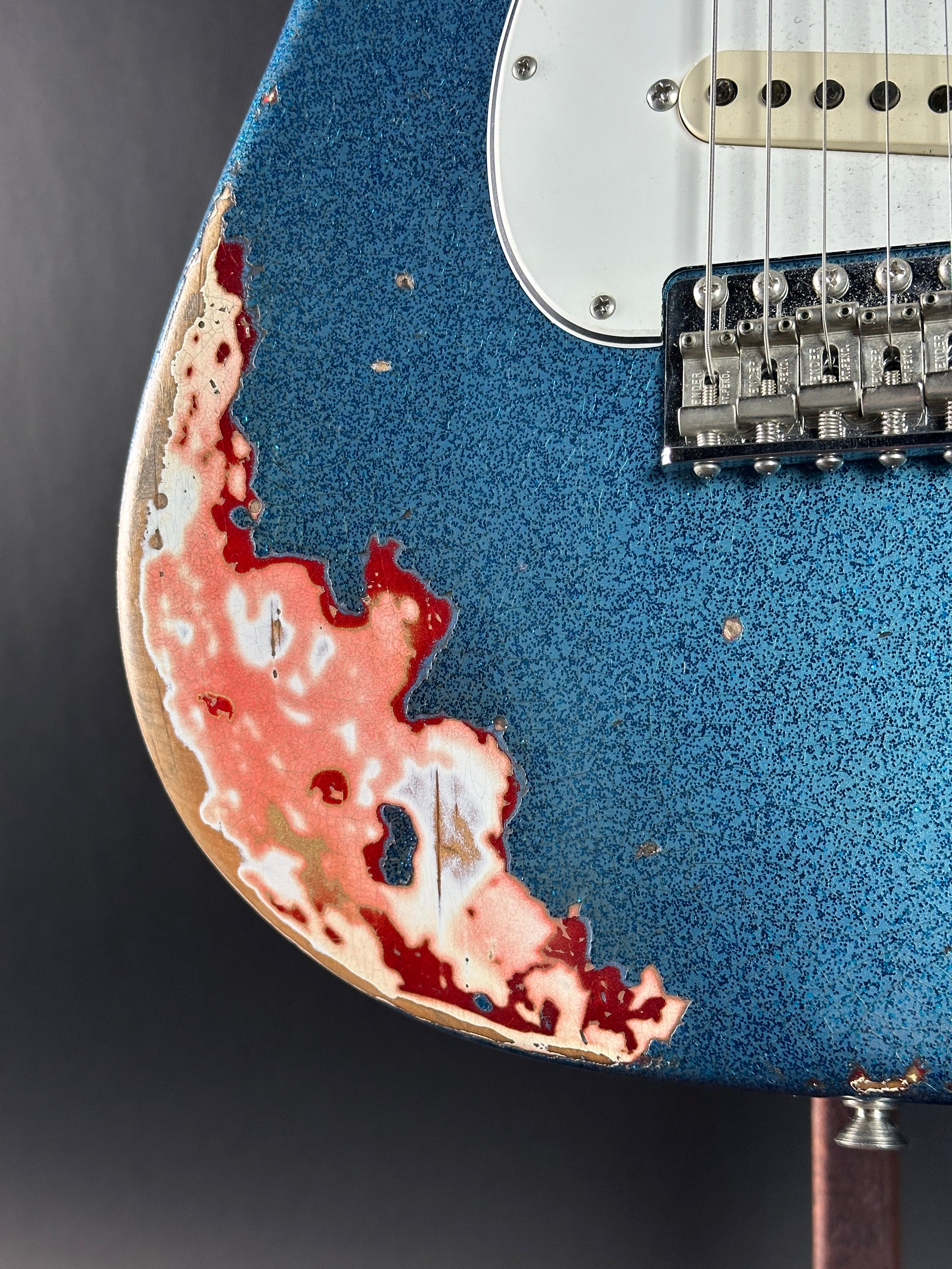 Bottom left of body of Used Fender Custom Shop GC Tex Strat Heavy Relic Blue Sparkle Over Candy Apple Red.