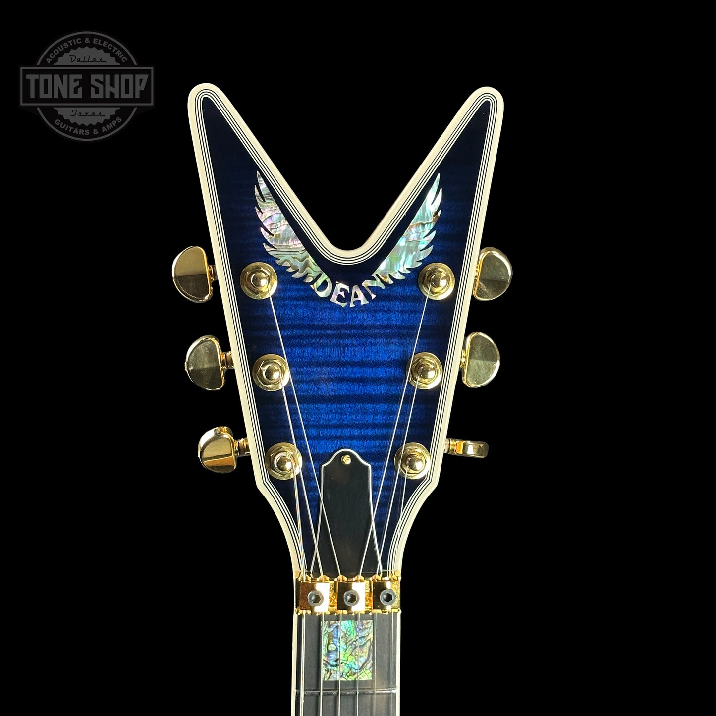 Front of headstock of Dean USA Custom Shop ML Trans Blue Flamed Maple Top Korina Body Gold Hardware.